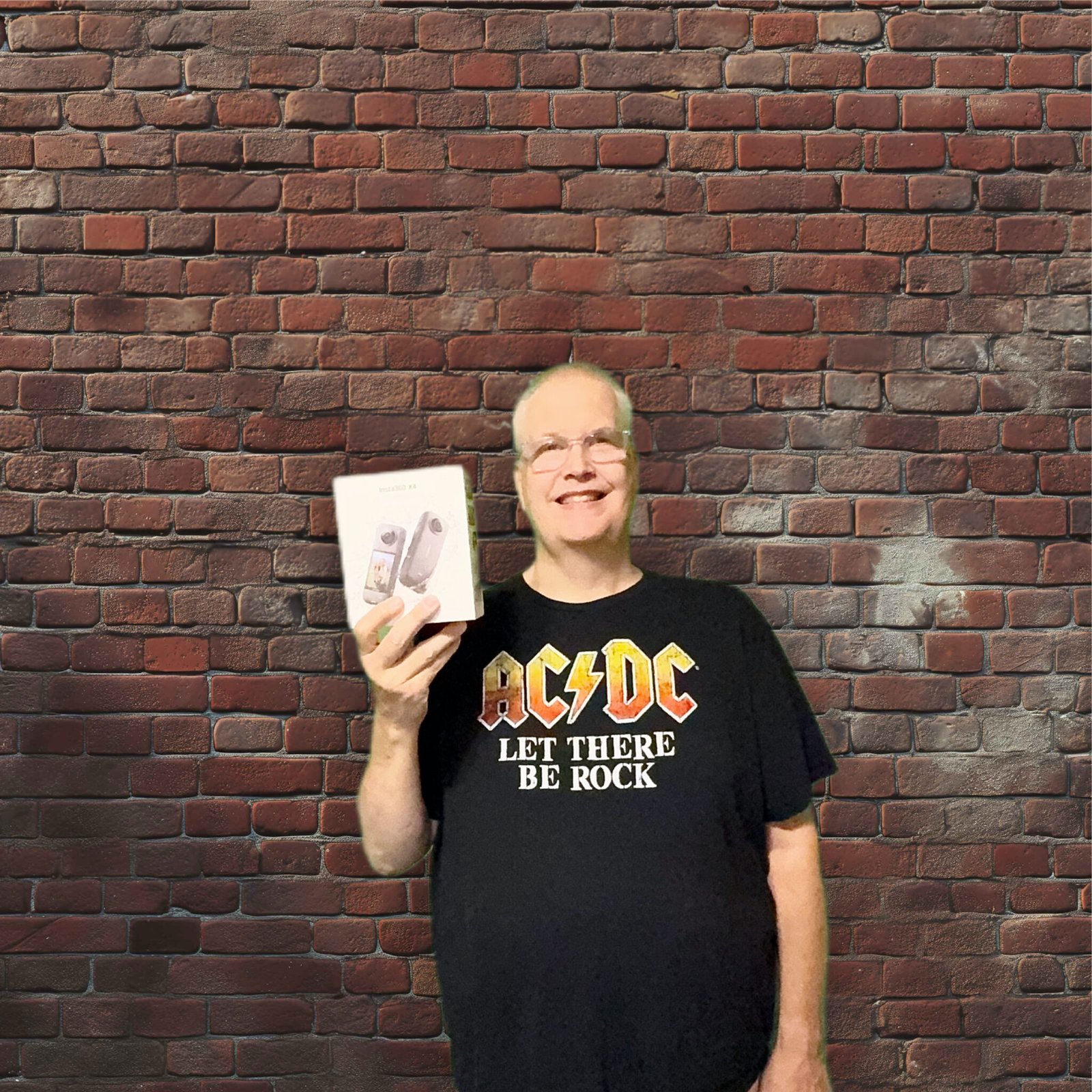 a man holding action camera box in front of a brick wall