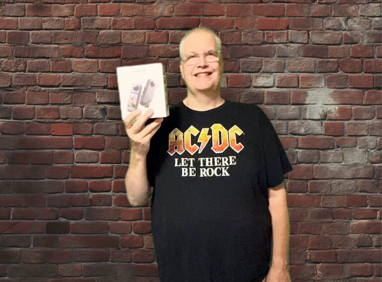 a man holding action camera box in front of a brick wall