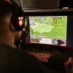 A gamer intensely playing a strategy game on a high-resolution monitor indoors.