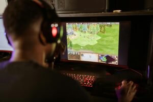 A gamer intensely playing a strategy game on a high-resolution monitor indoors.