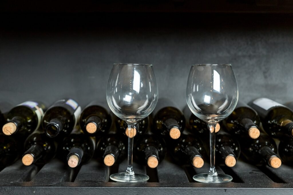 Many wine bottle and wine glasses in front of black wall. Wine tasting in the winery.copy space